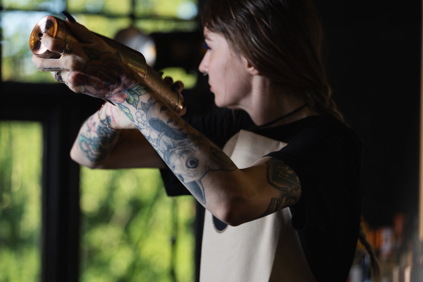 A bartender working the shaker in the window light