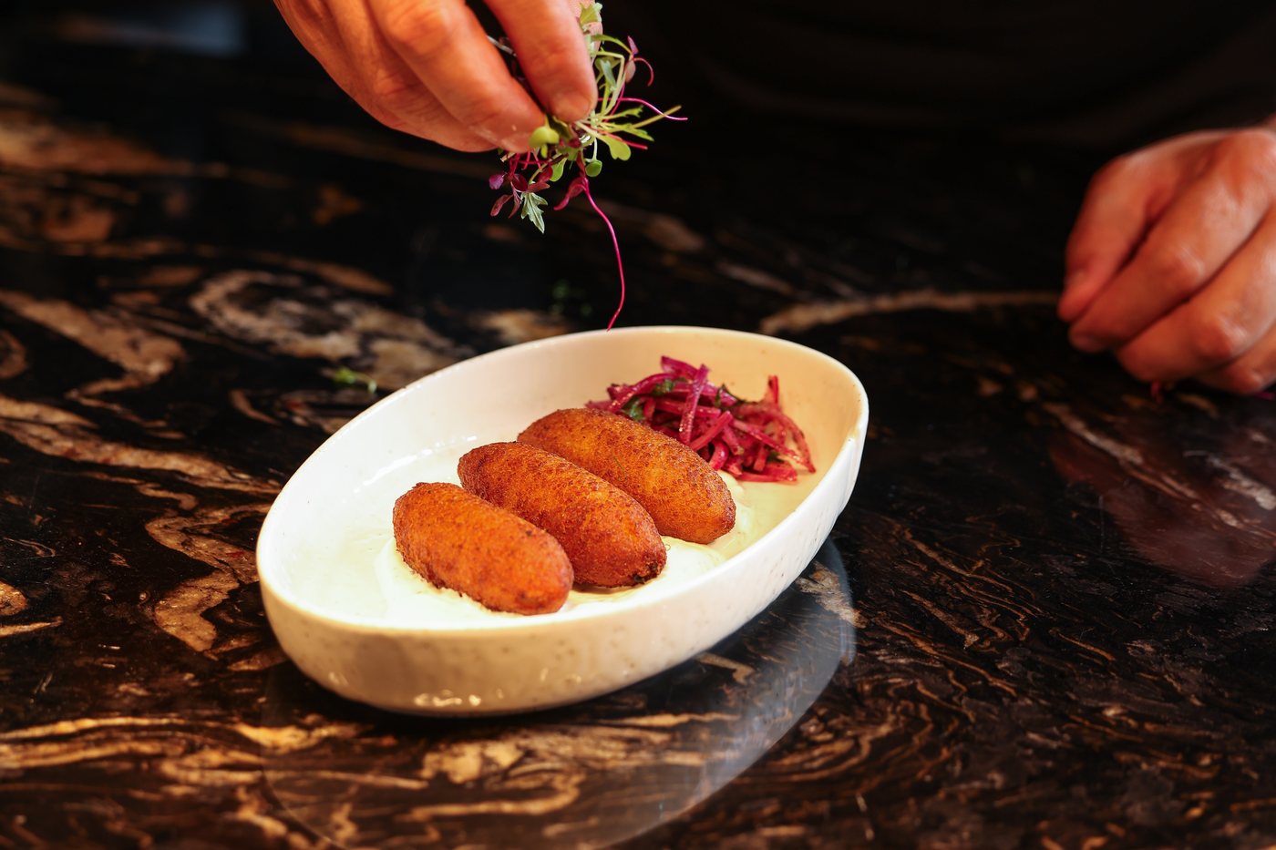 A chef finishing a mezze plate by hand