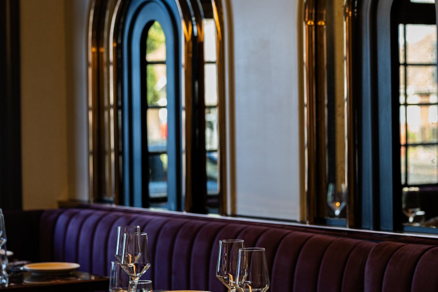Velvet banquettes beneath the arched windows