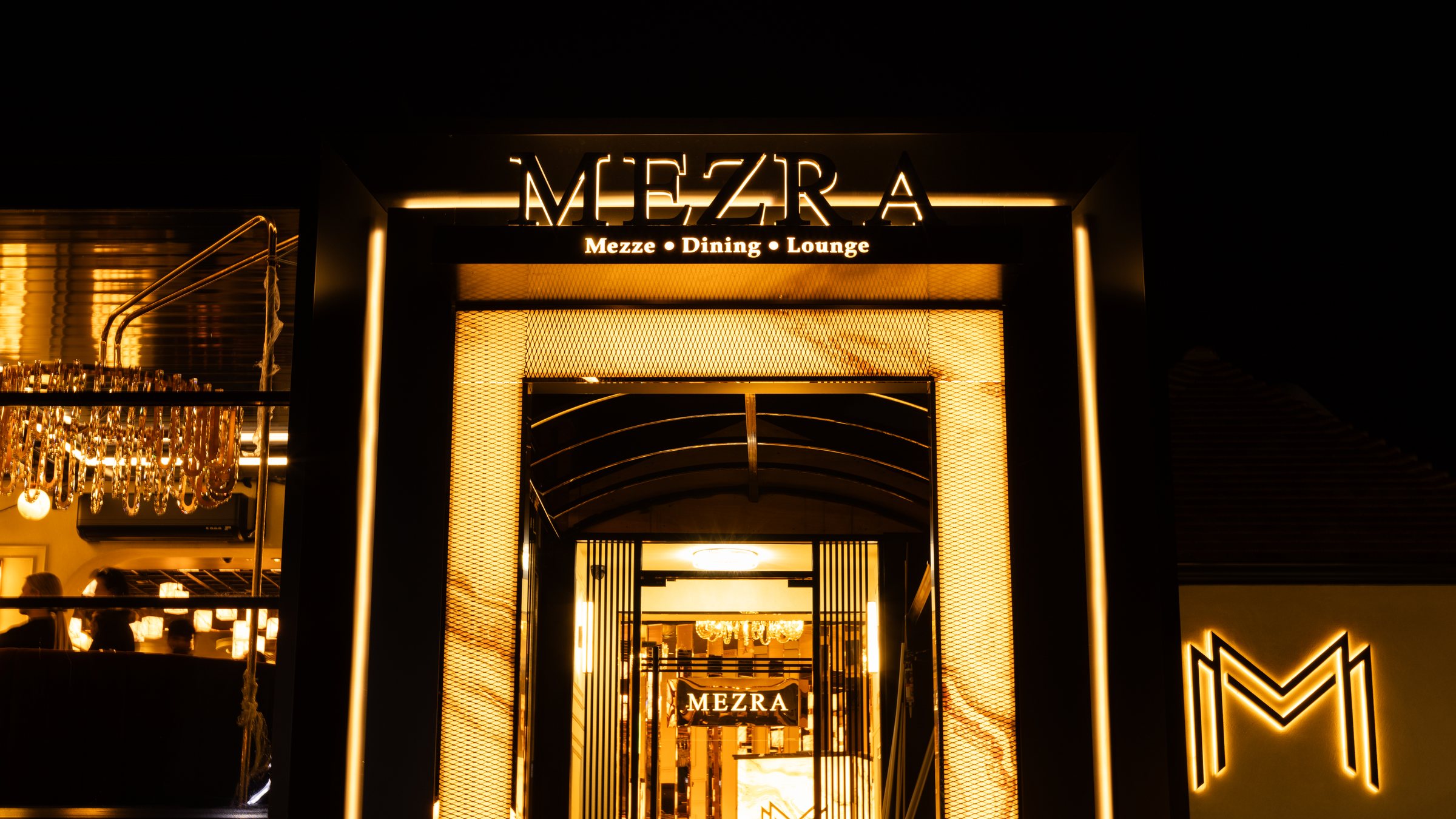 The lit entrance to Mezra after dark